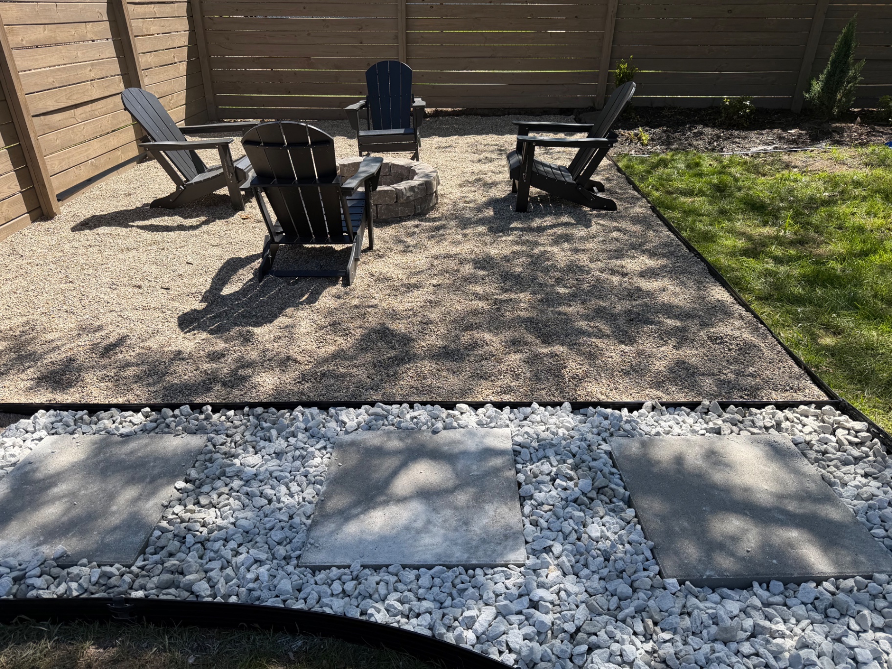 Adirondack chairs around a stone fire pit on pea gravel